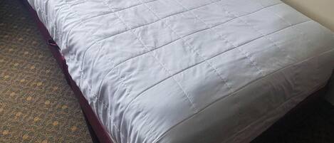 A single bed with a white duvet in a hotel room.