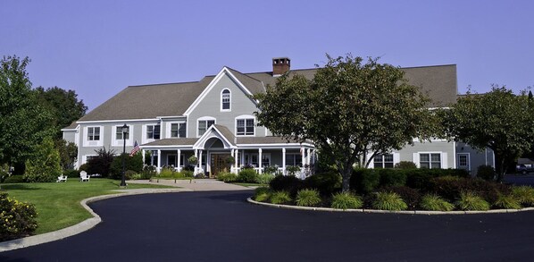 A large, two-story house with a wrap-around porch, a chimney, and a well-maintained lawn.