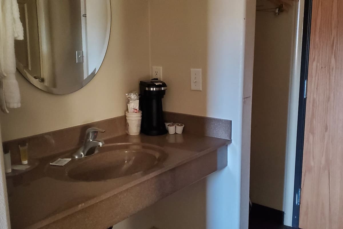 A bathroom with a sink, mirror, and a coffee machine.