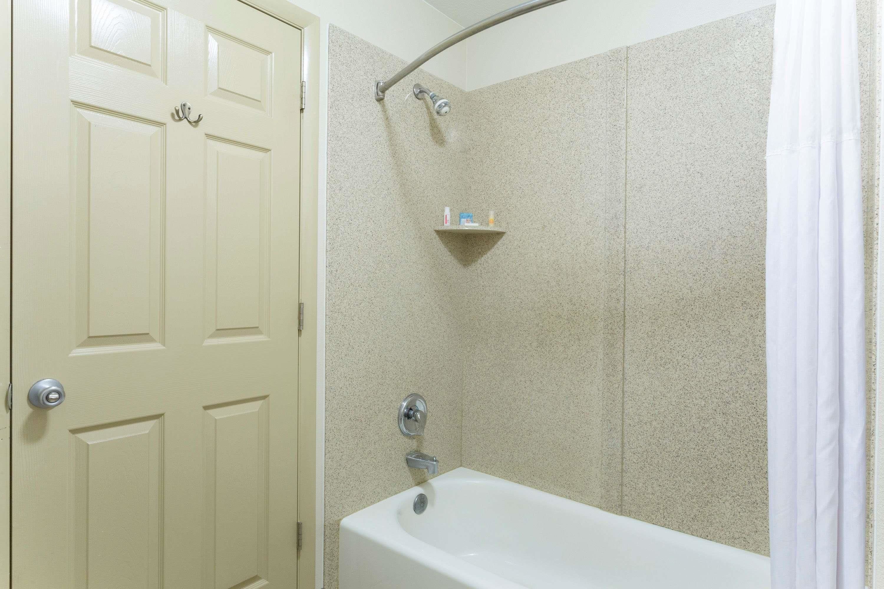 Un baño con bañera, ducha y una puerta con pomo.