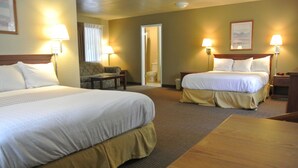 A hotel room with two beds, a chair, a table, and two bedside lamps.