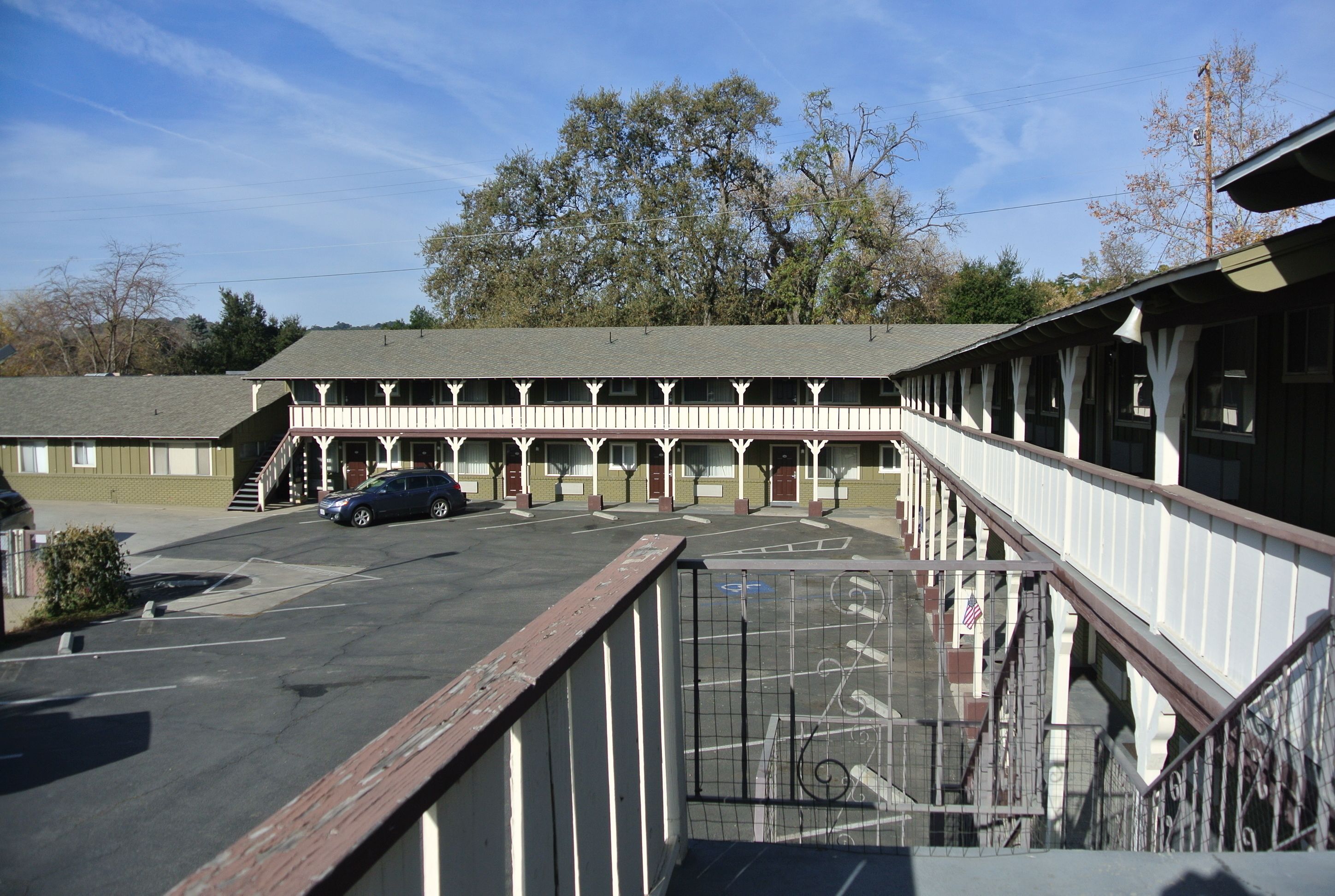 A motel with a covered parking area and a staircase leading to the entrance.