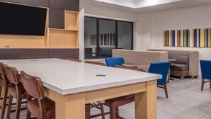 A modern meeting room with a large table, chairs, and a seating area with patterned cushions. - Holiday Inn Express & Suites Laplace by IHG (LaPlace)