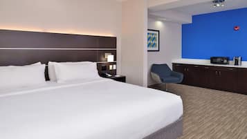 A hotel room with a large bed, a desk with a chair, a microwave, and a coffee maker.