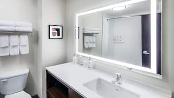 A modern bathroom with a white sink, a large mirror, and neatly arranged towels.