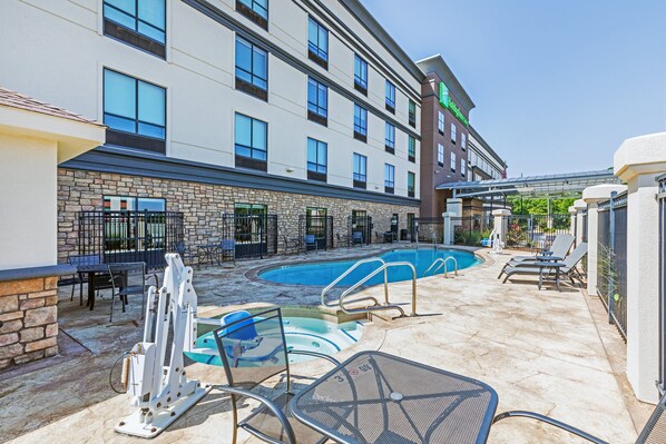 A hotel with a swimming pool, outdoor seating, and a stone facade. - Holiday Inn Stillwater - University West by IHG (Stillwater)