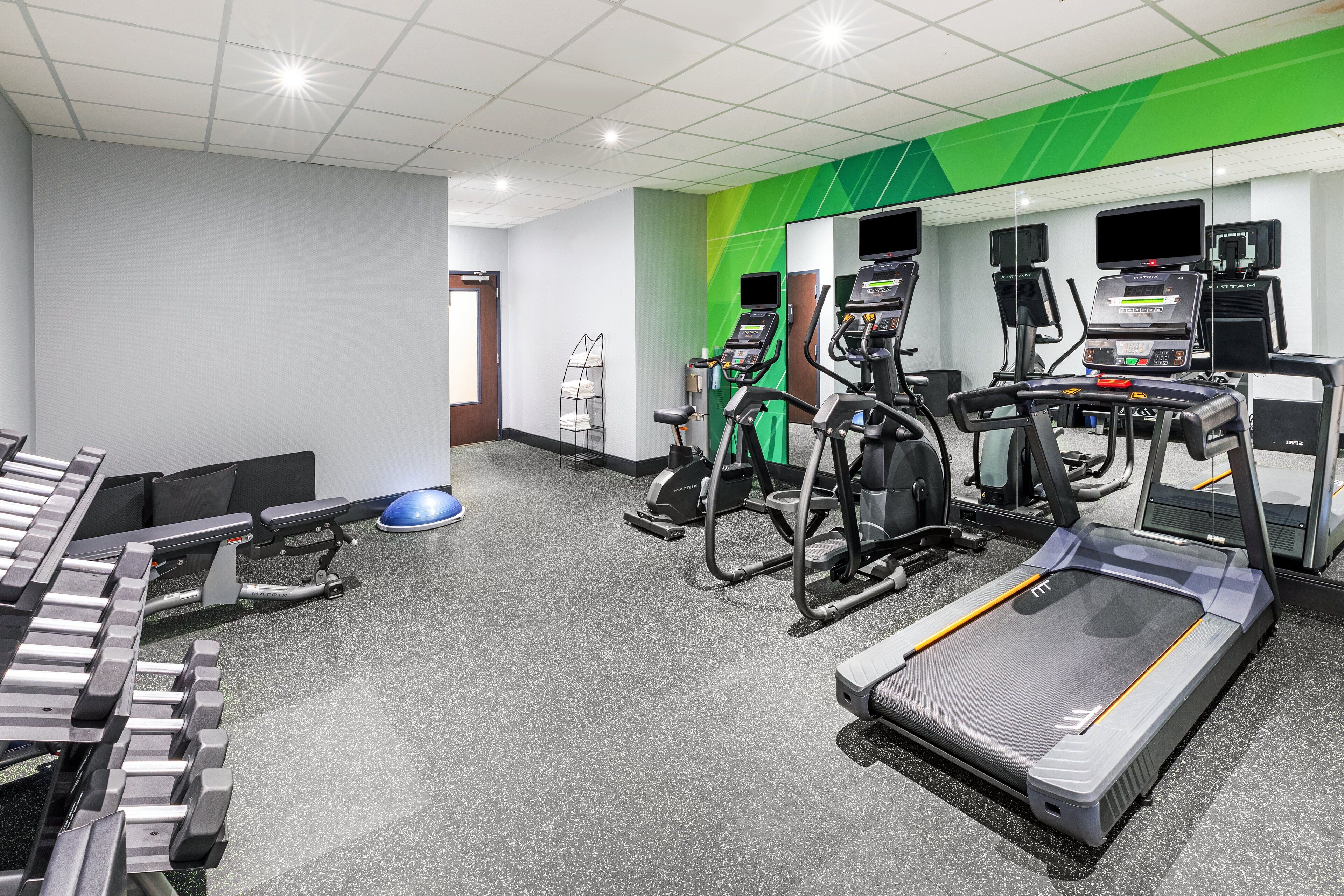 A gym with treadmills, elliptical machines, and weight benches.