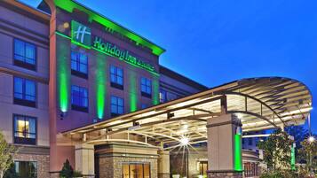A Holiday Inn & Suites with a covered entrance and a stone facade.