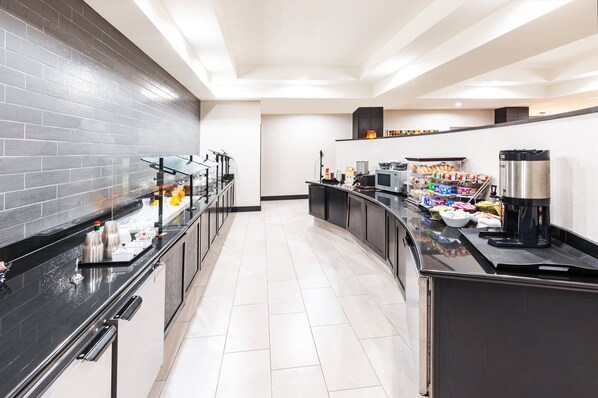 A modern kitchen with a black countertop, stainless steel appliances, and a variety of food items. - Holiday Inn Stillwater - University West by IHG (Stillwater)