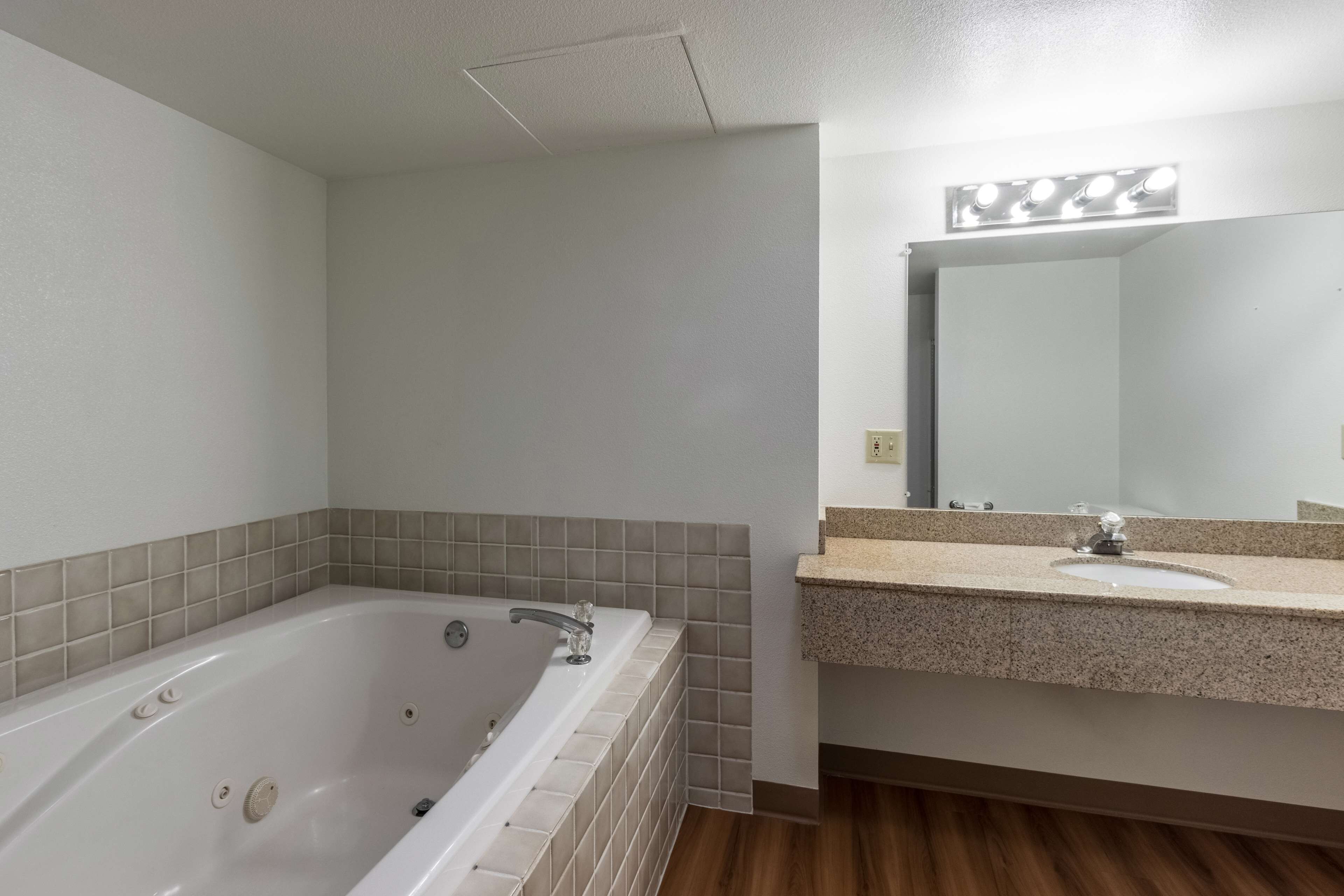 A bathroom with a bathtub, a sink, and a mirror.