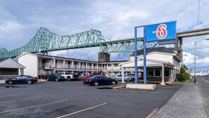A motel with a sign indicating no vacancy, a parking lot with several cars, and a green bridge in the background. - Motel 6 Astoria, OR (Astoria)