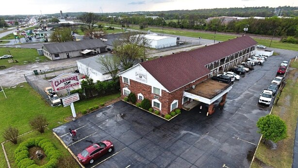 A large building with a parking lot, a sign for 'Claremont Motor Inn', and a red car parked in the lot. - Claremore Motor Inn (Claremore)
