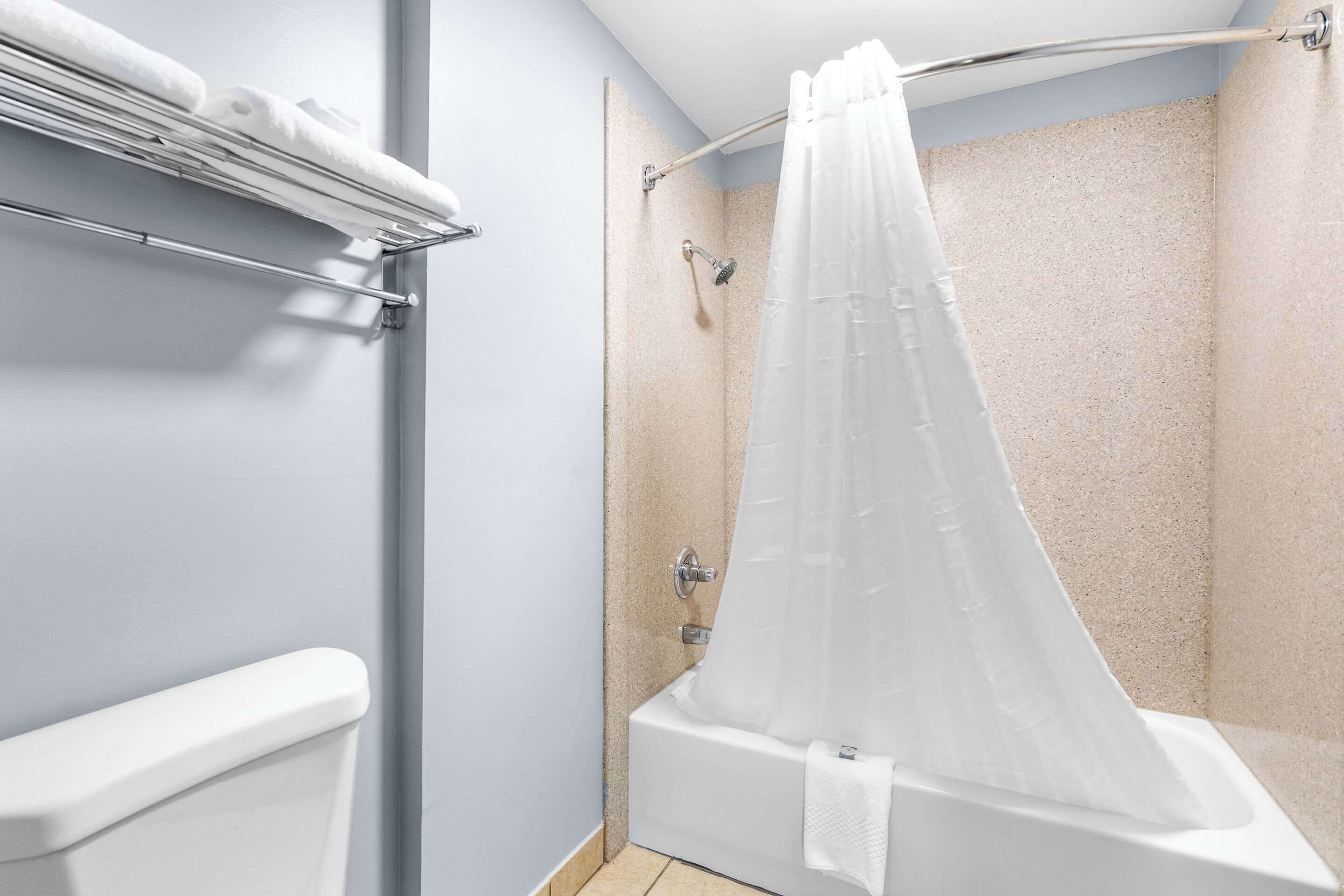 A shower area with a bathtub, a towel rack, and a shower curtain.