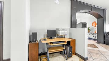 A home office setup with a desktop computer, printer, and monitor on a wooden desk.