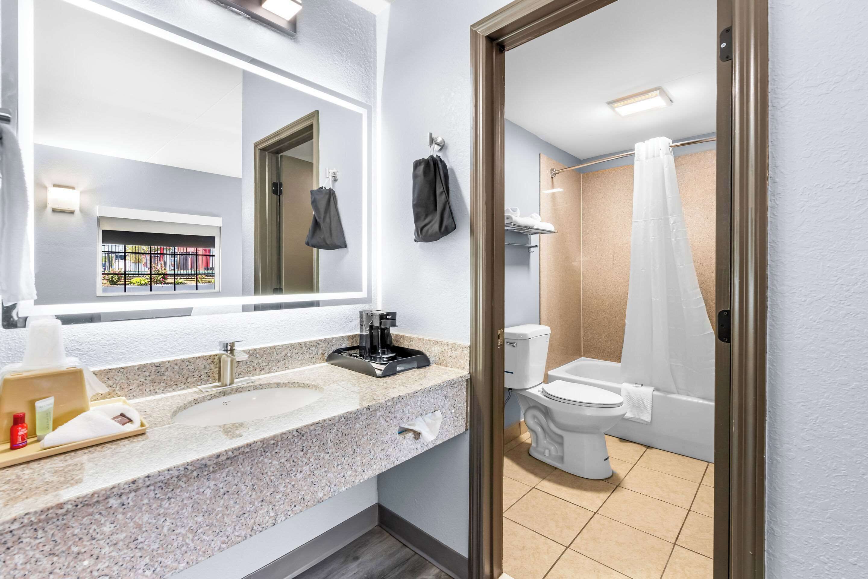 A modern bathroom with a granite sink, a coffee maker, and a toilet.