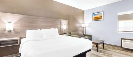 A modern hotel room with a large bed, bedside tables, a chair, a desk, and a picture on the wall.