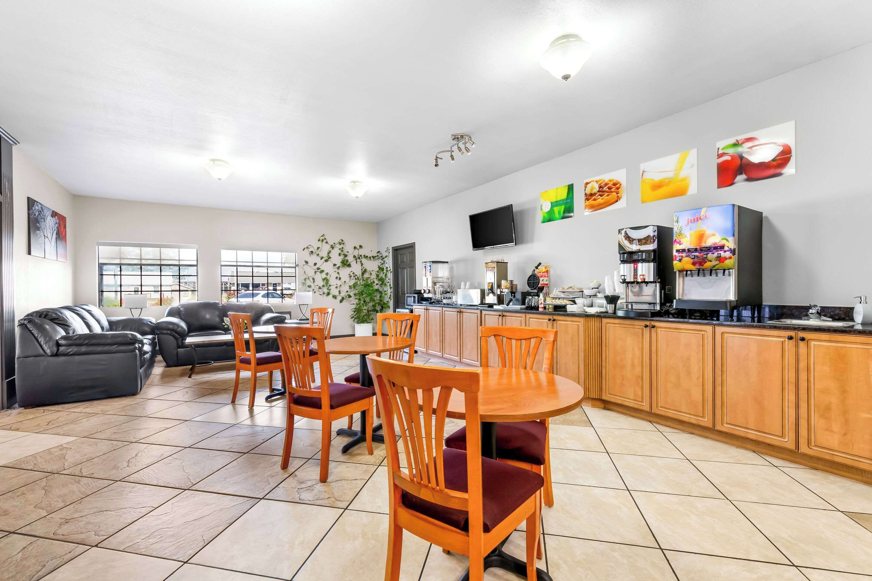 A spacious living area with a dining table and chairs, a kitchen with a coffee machine, and a TV mounted on the wall.