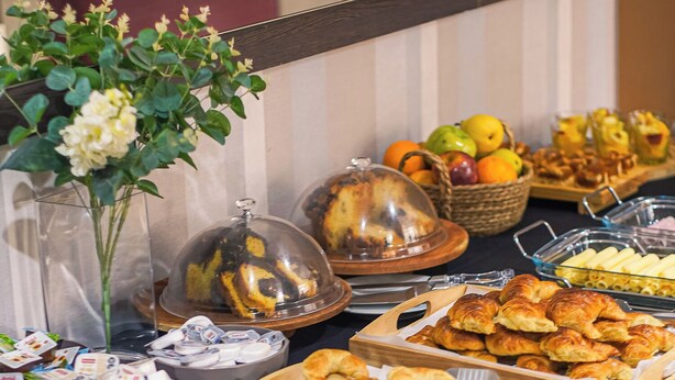 A buffet table with various food items, including bread, pastries, and fruits. - Sarum Hotel Design (Buenos Aires)