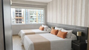 A hotel room with two beds, a nightstand, a lamp, and a window with a city view. - Sarum Hotel Design (Buenos Aires)