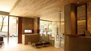 A modern reception area with a wooden ceiling, glass partitions, and a bench. - Sarum Hotel Design (Buenos Aires)
