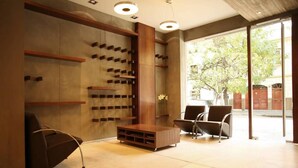 A modern waiting area with a wooden console table, two chairs, and a wall-mounted shelf unit. - Sarum Hotel Design (Buenos Aires)