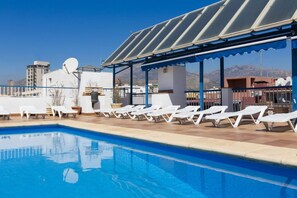 Una piscina al aire libre, sombrillas, sillones reclinables de piscina