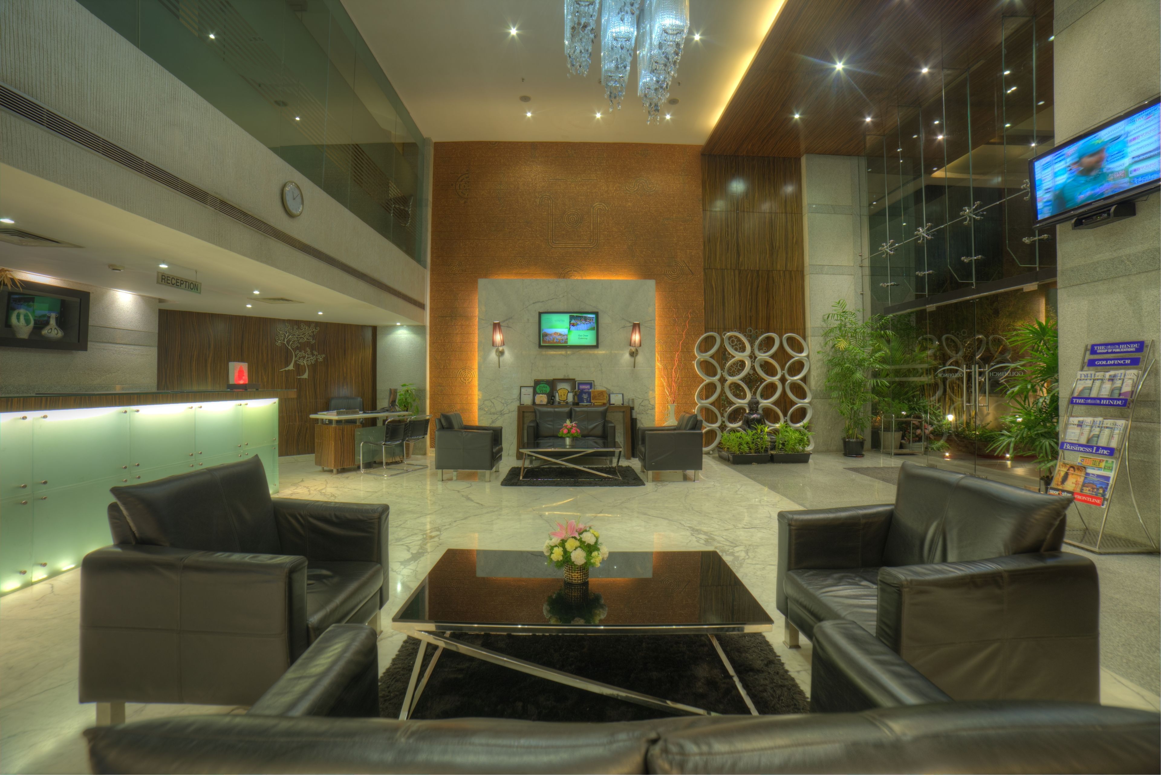 Un lobby moderno con mostrador de recepción, área de estar y una pantalla de televisión.