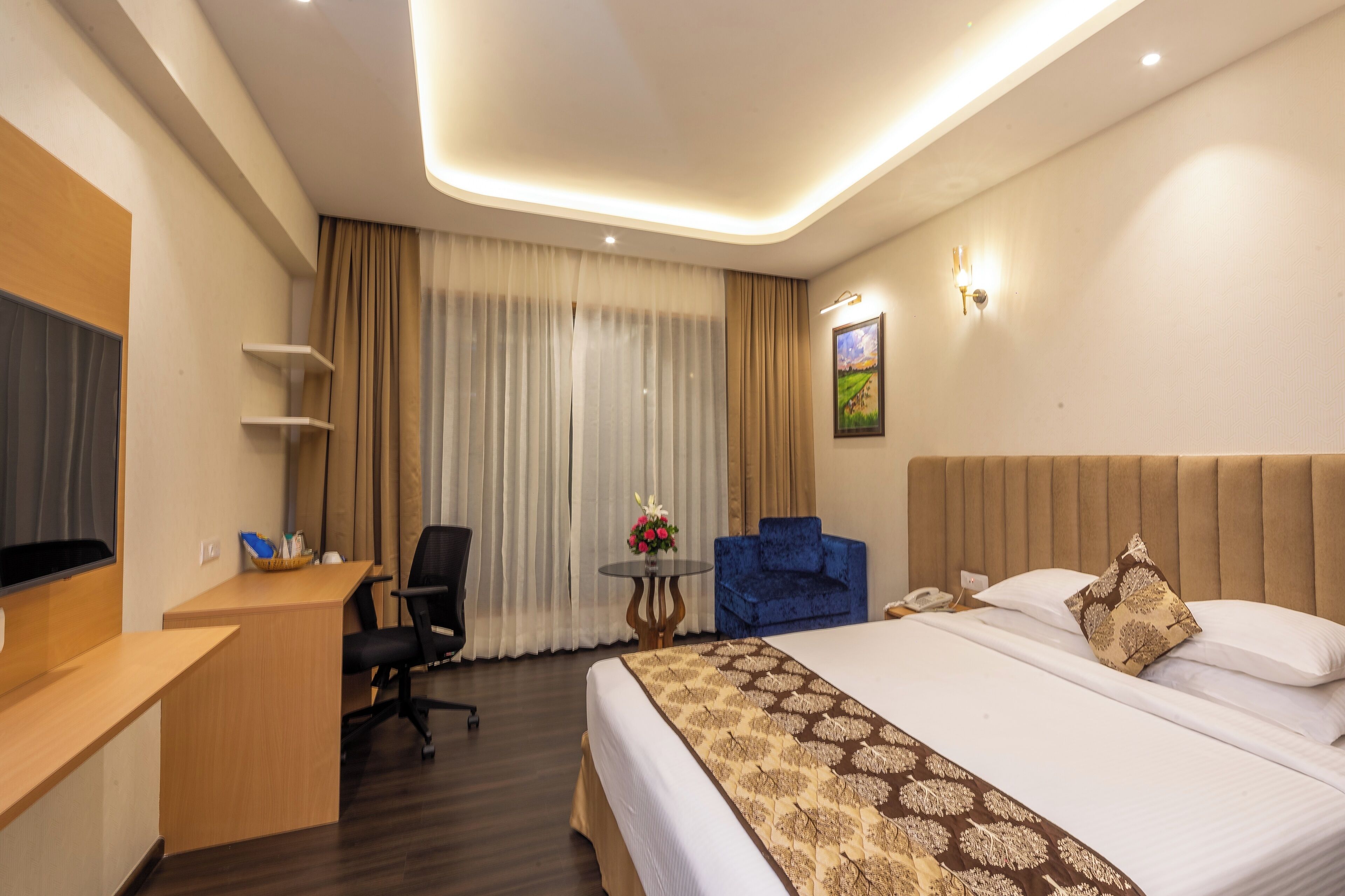 Ein Hotelzimmer mit einem Bett, einem Schreibtisch, einem Stuhl, einem kleinen Tisch mit einer Vase und einem blauen Sessel.