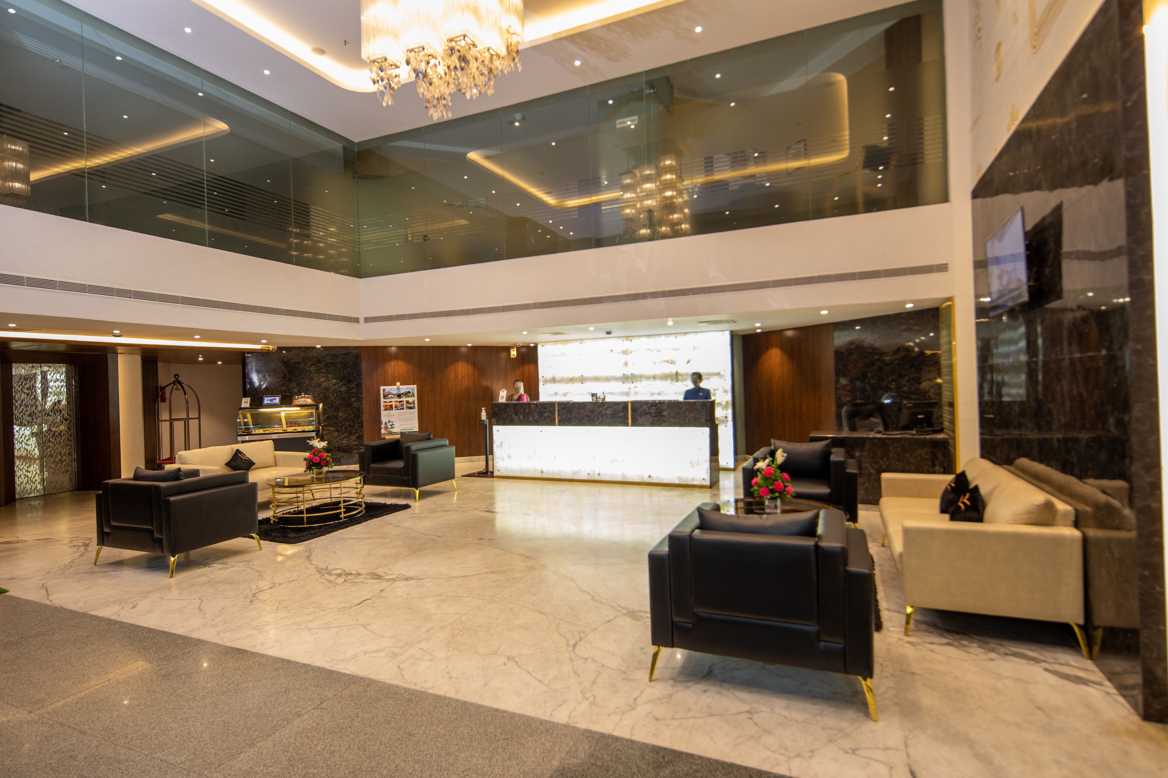 A modern lobby with a reception desk, seating area, and a glass ceiling.