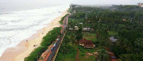 Eine Küstenstraße mit Zugang zum Strand, gesäumt von Grünflächen und Wohngebäuden.