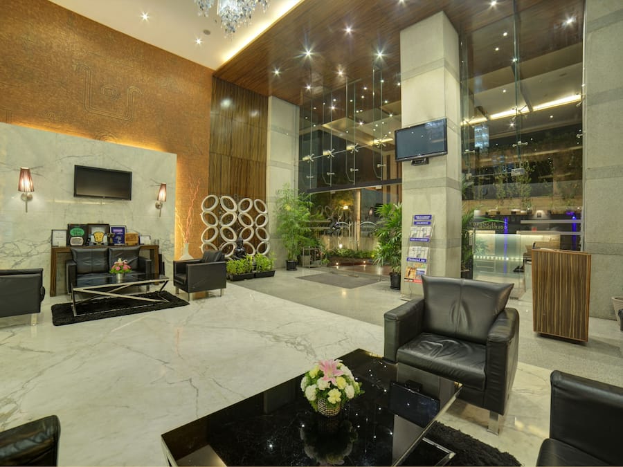 A modern lobby with a marble floor, leather seating, a flat-screen TV, and a reception desk.