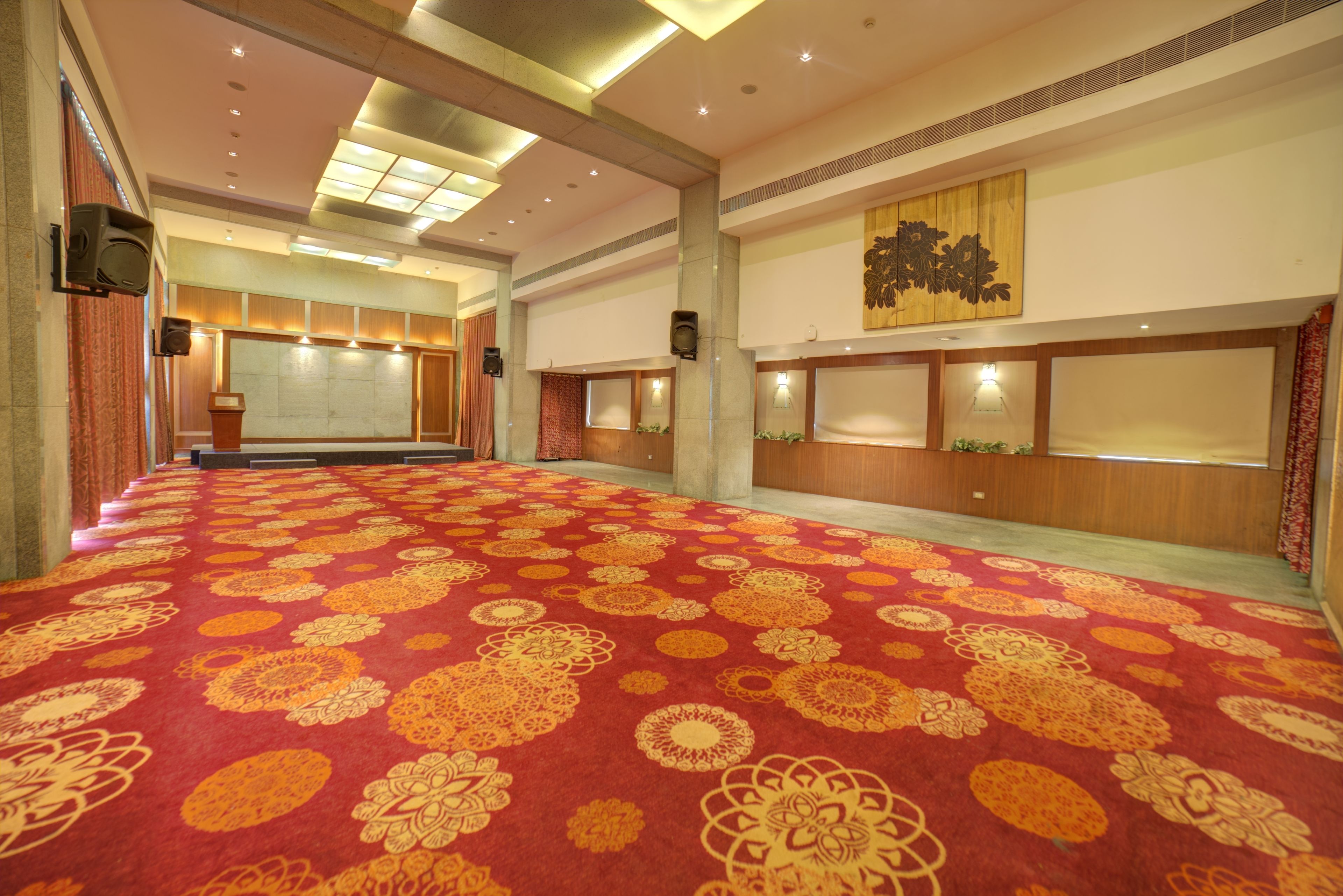 A spacious hall with a patterned carpet, recessed lighting, and a large wall-mounted artwork.