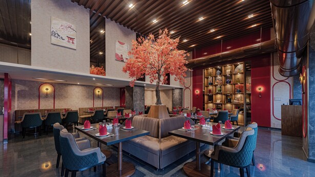 A modern restaurant with booths and tables, a decorative tree, and traditional decor. - Goldfinch Hotel Mangalore (Mangaluru)