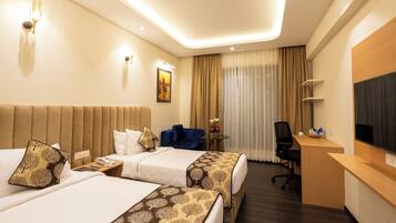 A hotel room with two beds, a desk, a chair, a TV, and a window with curtains.