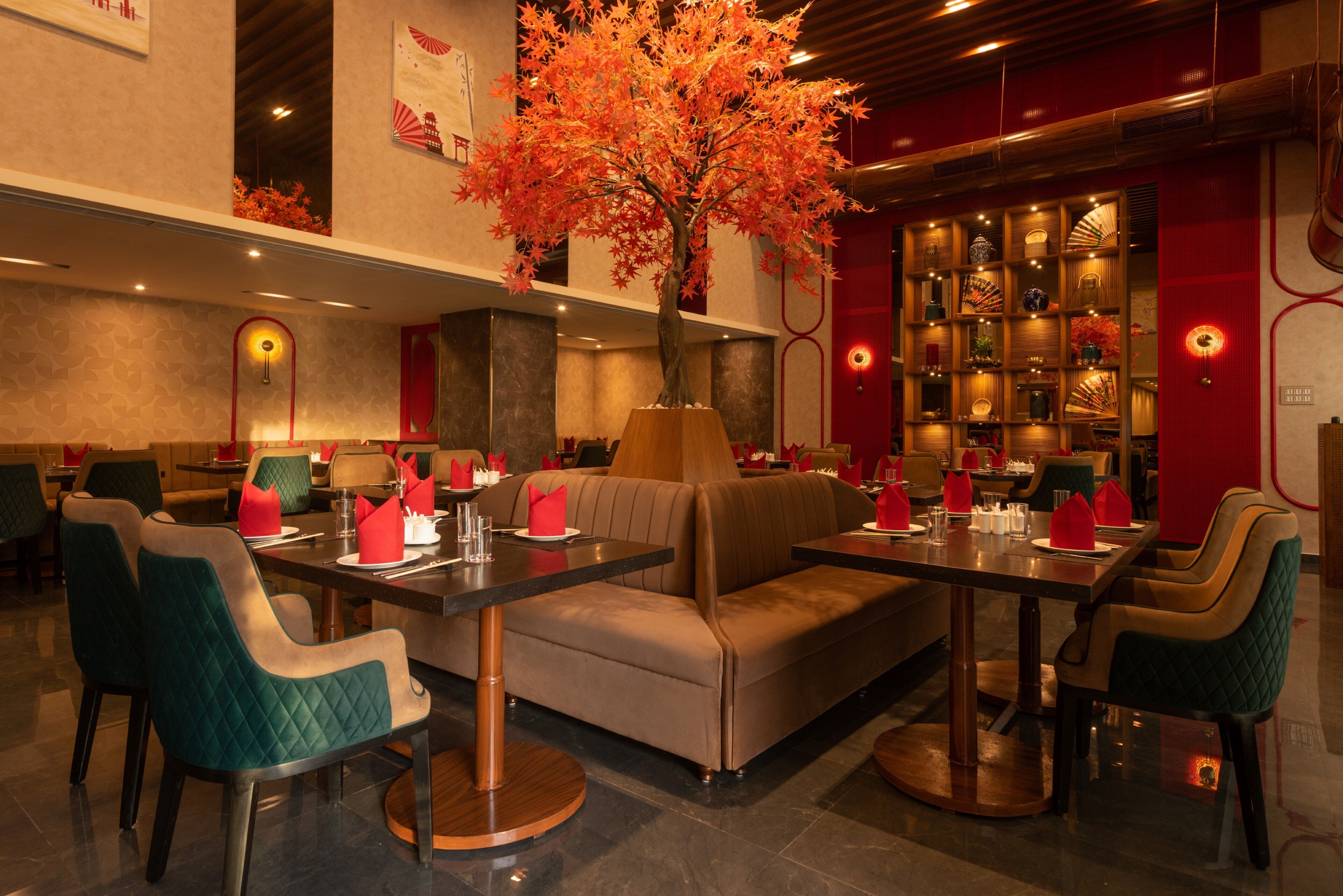 A restaurant with booths, tables, and a decorative tree.