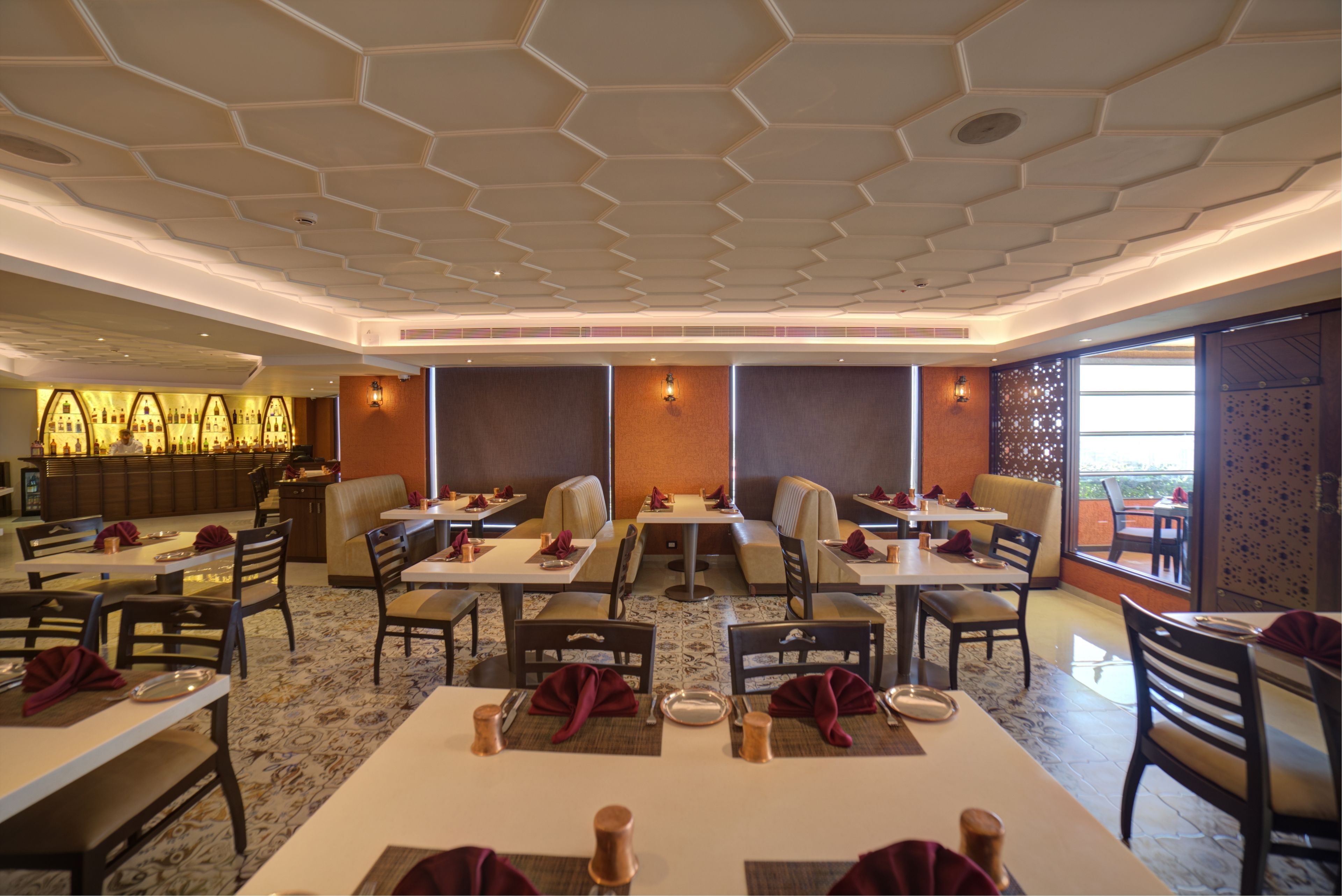 A restaurant with hexagonal ceiling design, multiple seating areas, and a bar counter.