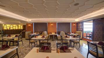 A restaurant with hexagonal ceiling design, multiple seating areas, and a bar counter.
