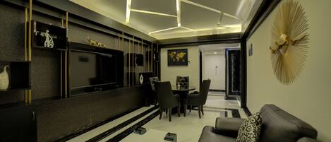A modern living room with a flat-screen TV, a coffee table, and a sofa.