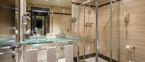 A modern bathroom with a glass shower enclosure, a glass sink, and a toilet.