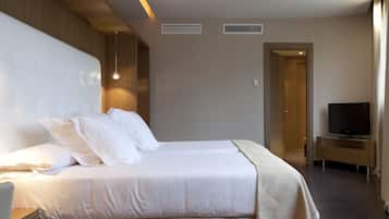 A hotel room with a large bed, a TV, and a wooden panel wall.