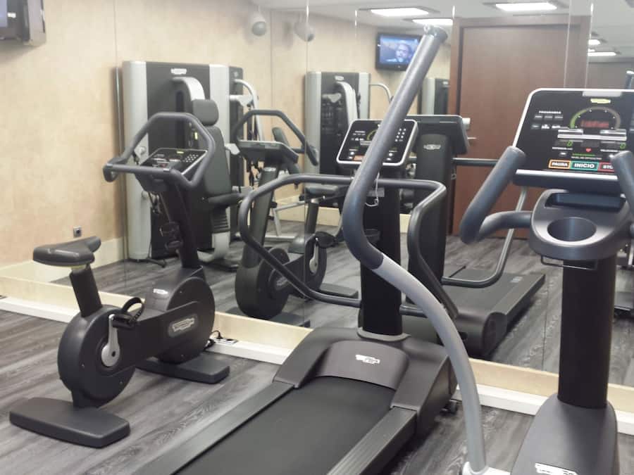 A gym with various exercise equipment including treadmills, stationary bikes, and weight machines.