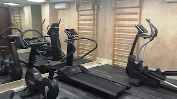 A gym with treadmills, elliptical machines, and a mirrored wall.