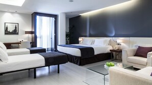 Una habitación de hotel moderna con una cama grande, un sofá, un escritorio y una mesa de centro de vidrio.