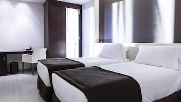A hotel room with two beds, a desk, and a chair.