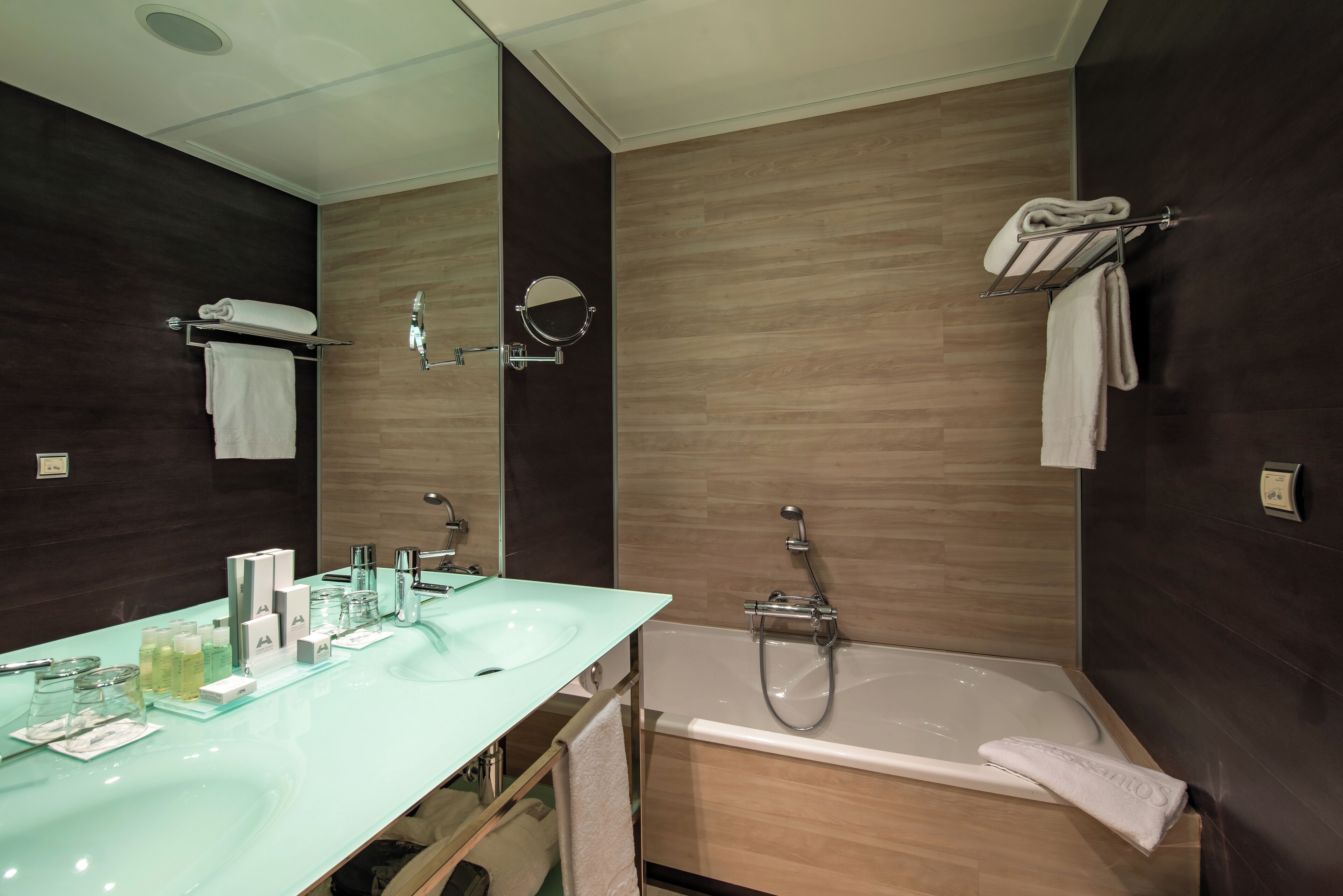 Un baño moderno con un lavabo de vidrio, una bañera y paredes de madera.