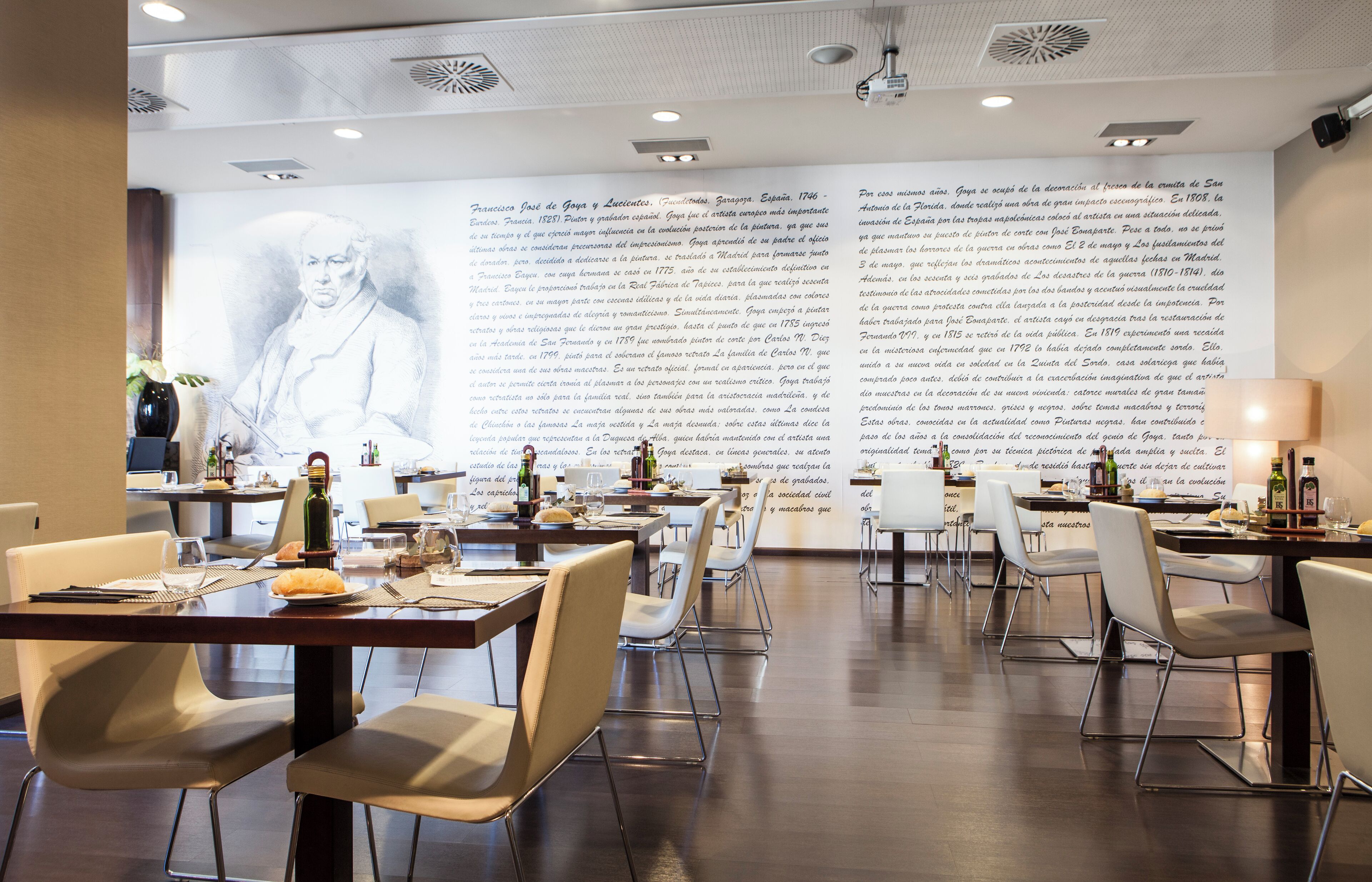Een restaurant met gedekte tafels, een grote muur met tekst en een modern interieur.