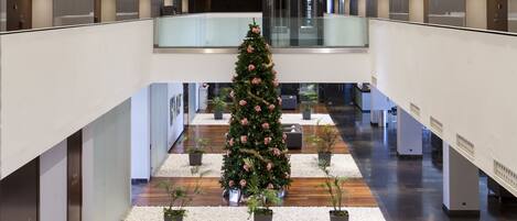 A multi-level atrium with a Christmas tree, potted plants, and seating areas.