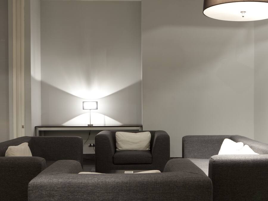 A modern room with a sofa set, a standing lamp, and a painting on the wall.