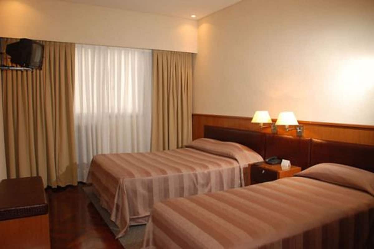 Habitación de hotel con dos camas, un televisor y dos lámparas de noche.