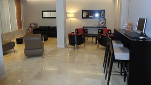 A modern hotel lobby with a reception desk, seating area, and a large mirror. - Hotel Napoleon (Buenos Aires)